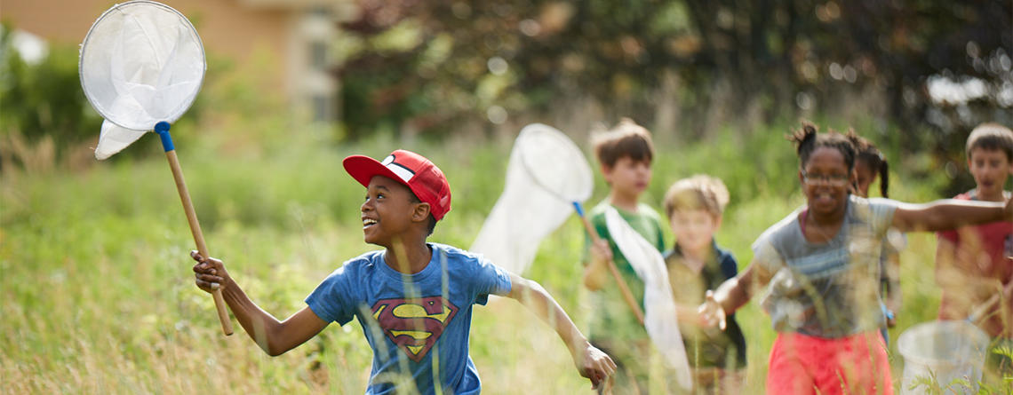 Campers running through a meadow with insect nets at BNC