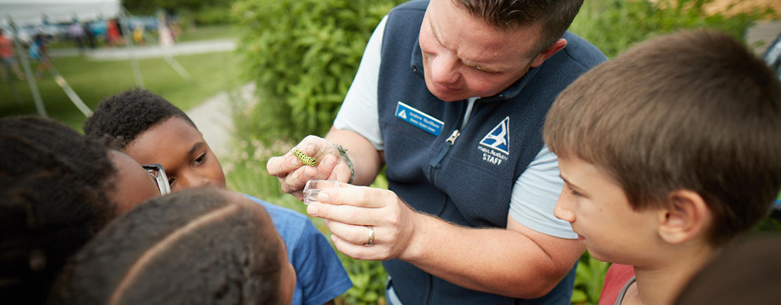 A BNC educator naturalist showing a caterpillar to a group of students