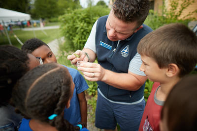 A BNC educator naturalist showing a caterpillar to a group of students