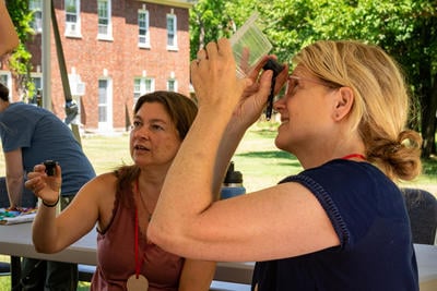 An educator examines an invertebrate using a hand lens during Nature School for Teachers professional development program