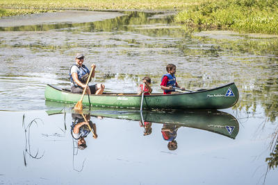 Family in a canoe exploring a pond at Mass Audubon's Arcadia Wildlife Sanctuary