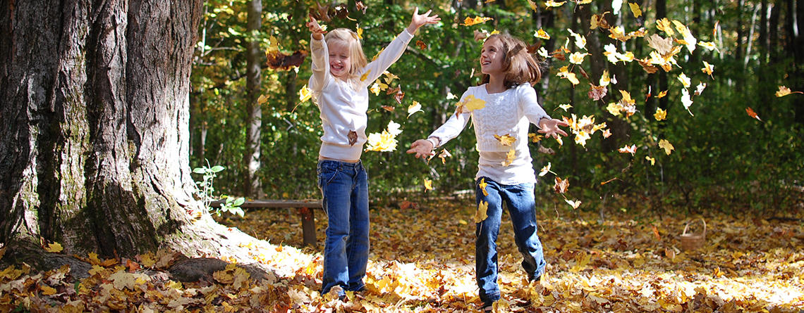 Kids throwing fall leaves in the air © Lisa Roberts