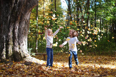 Two kids throwing fall leaves in the air © Lisa Roberts