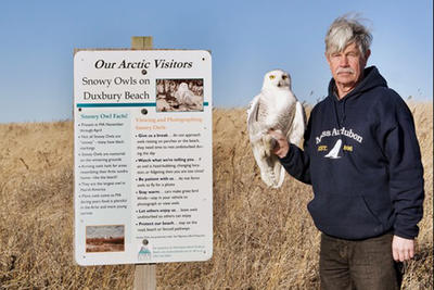 Norman Smith with a Snowy Owl in front of a Viewing Snowy Owl Guidelines sign