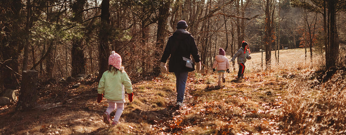 Parent with children of different ages walking on a trail in late fall