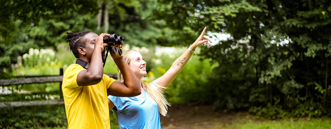 Young woman & man birding together at Drumlin Farm Wildlife Sanctuary in the summer
