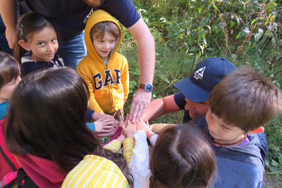 Children and educators putting their hands together in a huddle