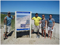 Staff and volunteers erect sign at Popponessett Beach.
