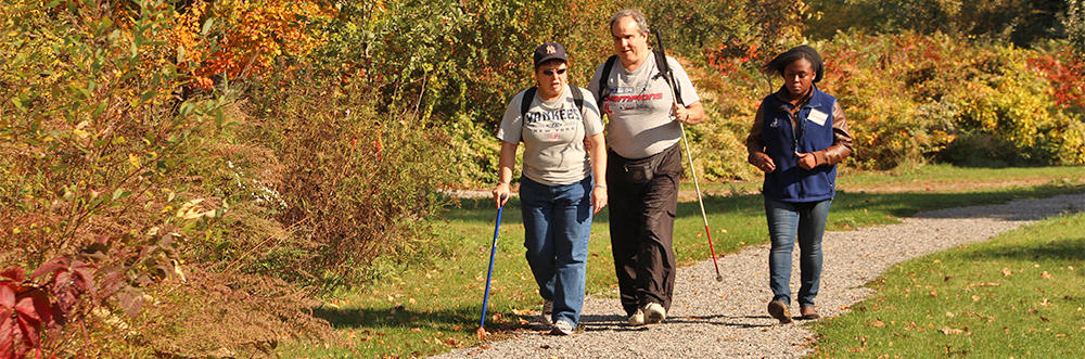 A Mass Audubon staff member walking with visitors on an accessible trail