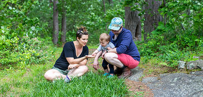 Young couple playing with their baby in the grass in summer