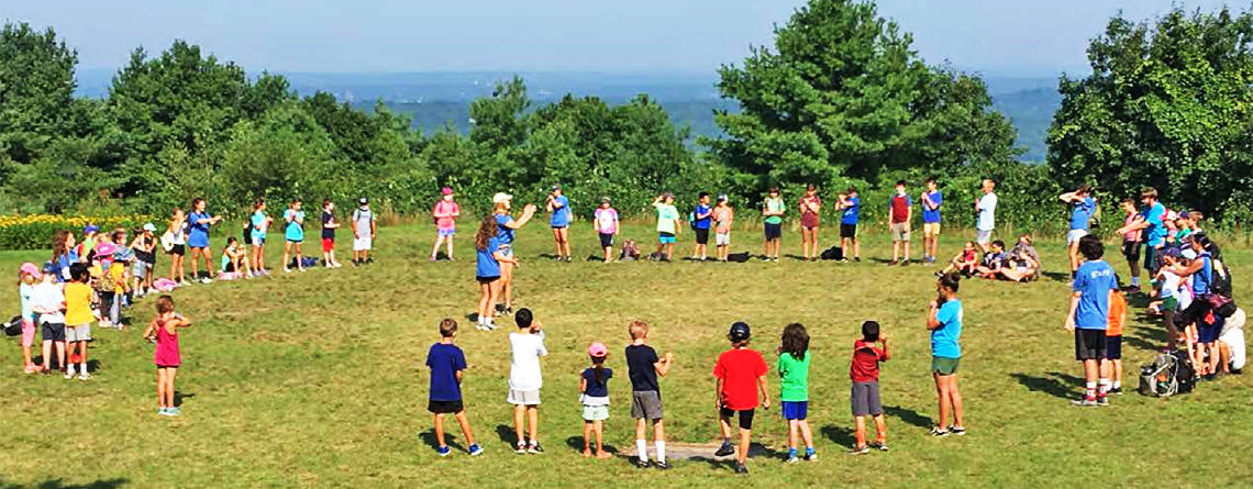 Campers & counselors gathering in a circle on Chickatawbut Hill at Blue Hills Nature Day Camp