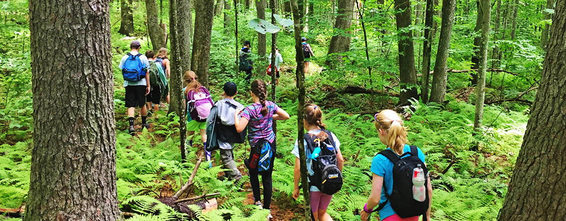 BMB campers hiking a trail through woods at the sanctuary