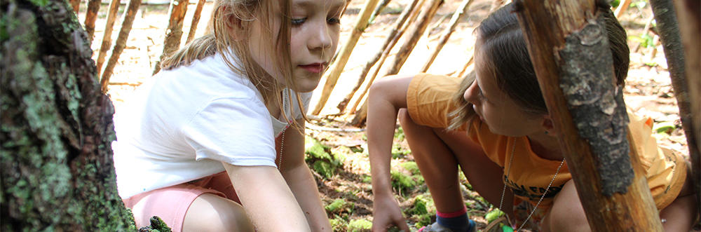 Two girls exploring a lean-to at Drumlin Farm