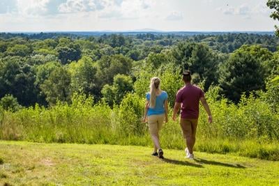Woman & man walking by overlook at Drumlin Farm Wildlife Sanctuary in summer