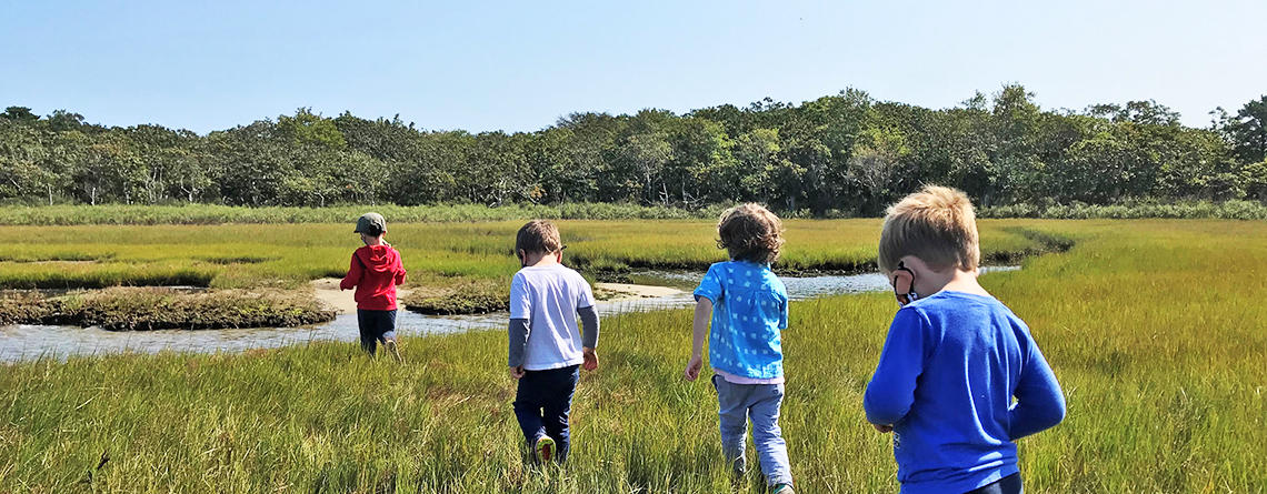 Young Fern & Feather Nature campers walking through a salt marsh