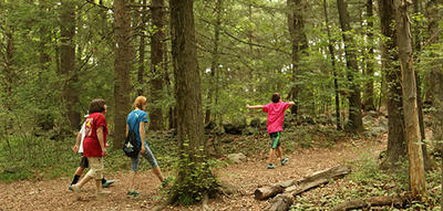 Family walking a wooded trail Habitat Education Center in summer