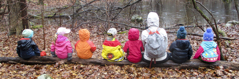 Preschoolers at Habitat sitting on a log by the vernal pool