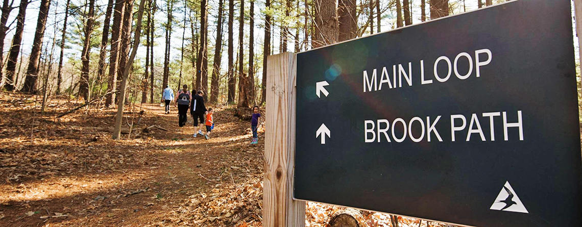Trail sign and hikers exploring MABA in early spring