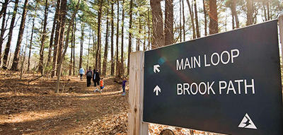 Trail sign and hikers exploring MABA in early spring