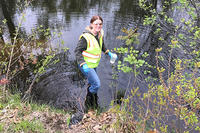 WQM volunteer taking a water sample from a river