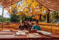 multiple children doing nature based art outside with foliage behind them