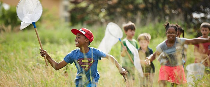 Campers running through field with insect nets