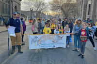 A group of children and adults holding a banner that reads "The Super Power of Science!"