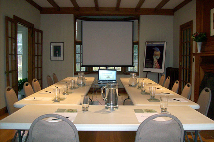 Living room with conference tables and screen set up for 12