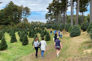 A group of people walking on a path through Pawtucket Farm
