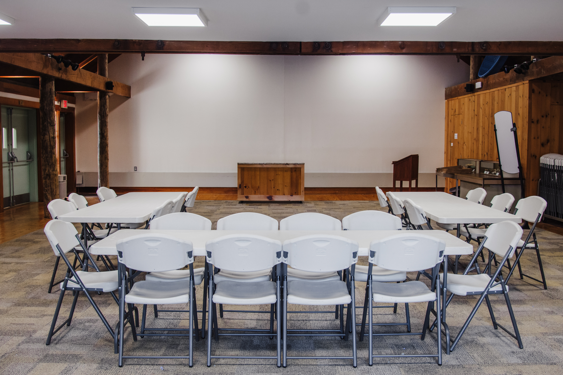 Auditorium set up with three tables and multiple chairs - photo taken from back of room