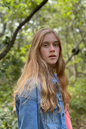 Young girl with long blonde hair looking at the camera.