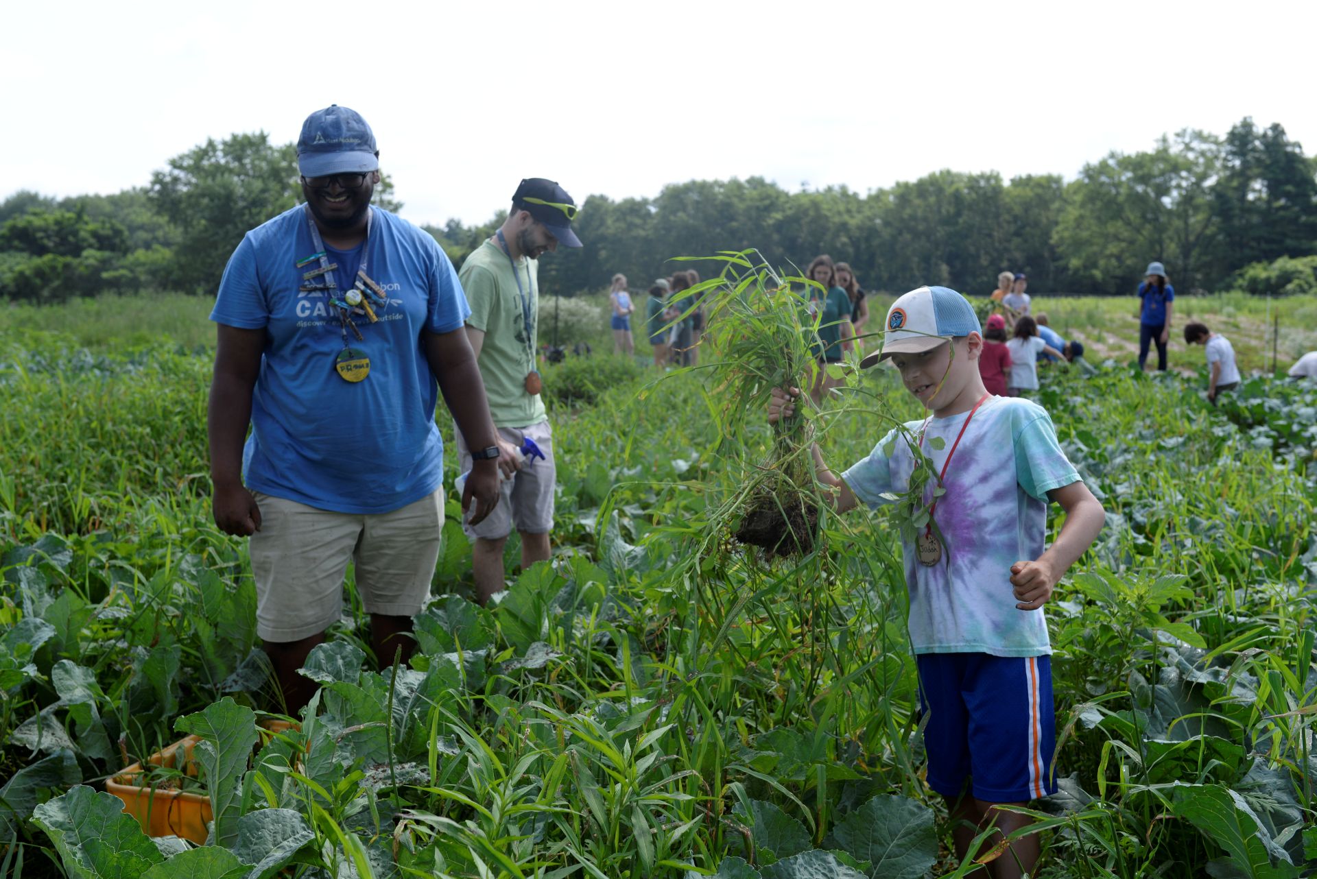 A counselor and camper work in the field, smiling.