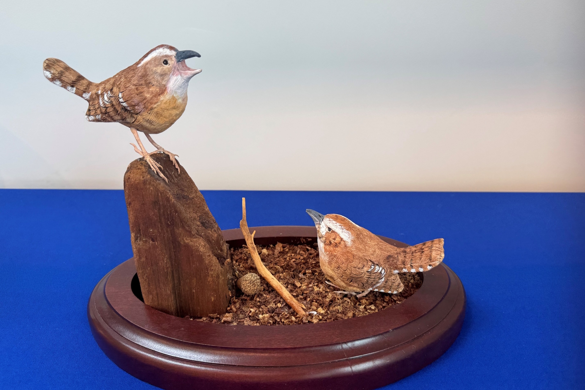 Sculpture featuring two Carolina Wrens foraging in dirt