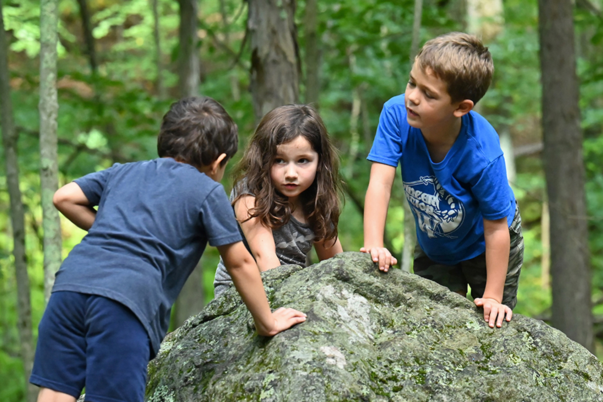 Two boys and one girl on a large rock