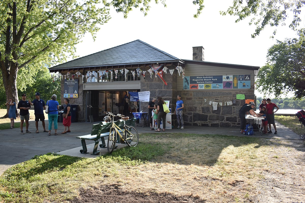 Magazine beach building with people out front and a bicycle next to a bench