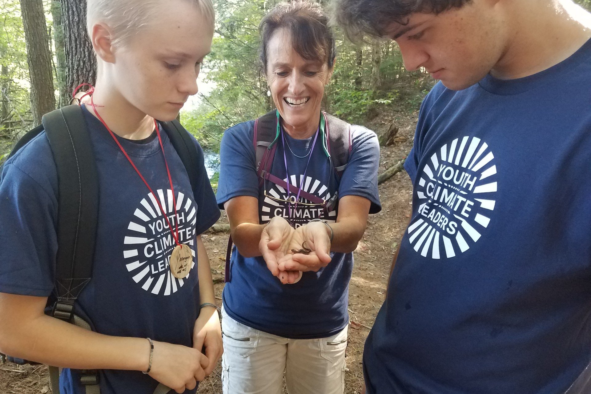 Two students looking at teacher holding salamander