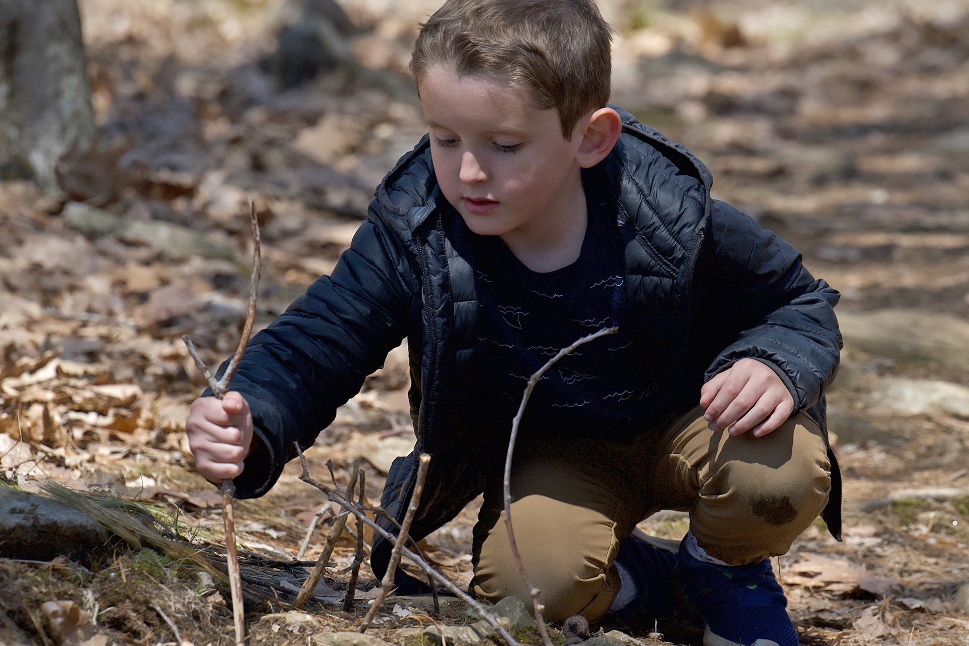 child inspecting sticks placed in the ground