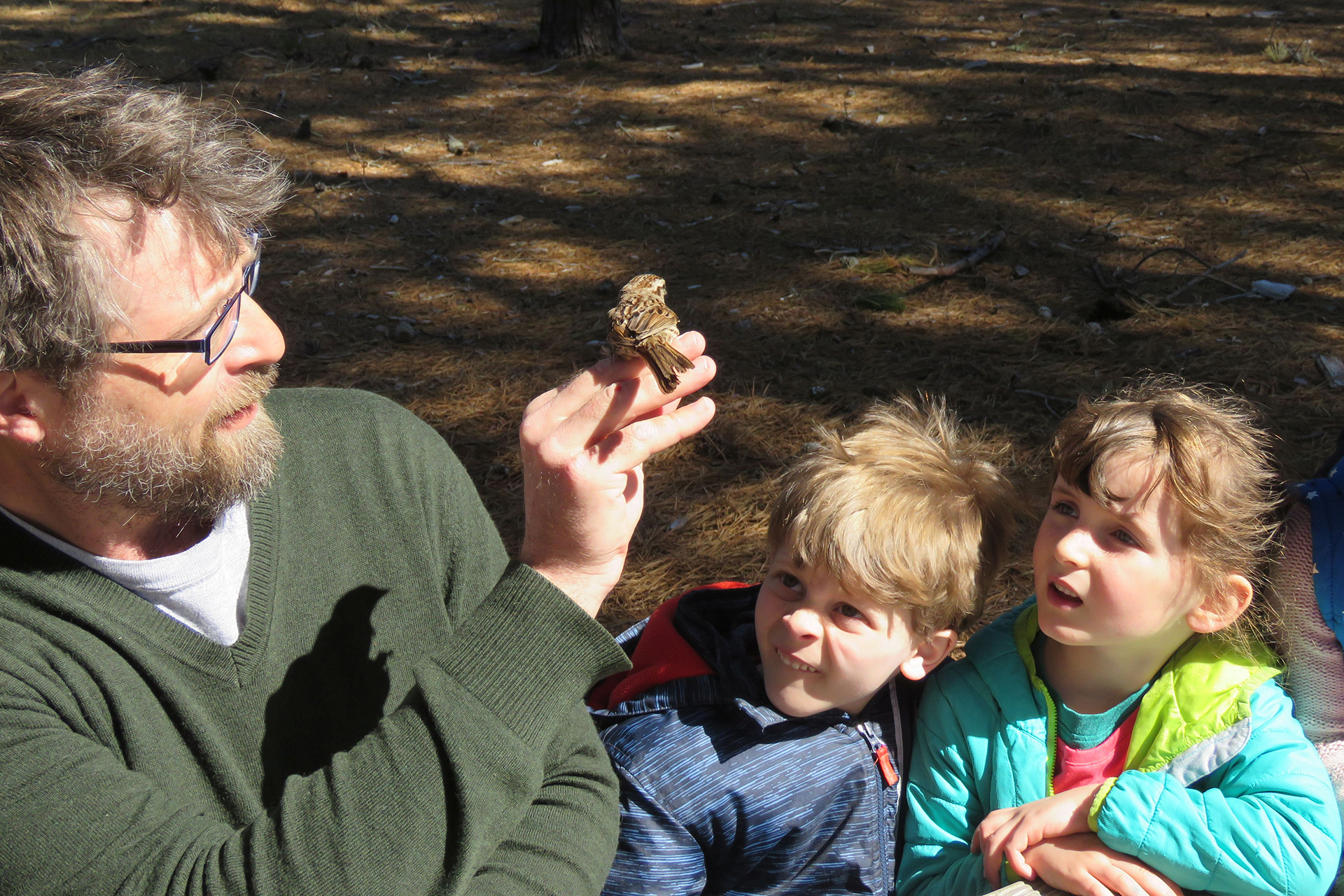 James Junda showing a bird to two young children