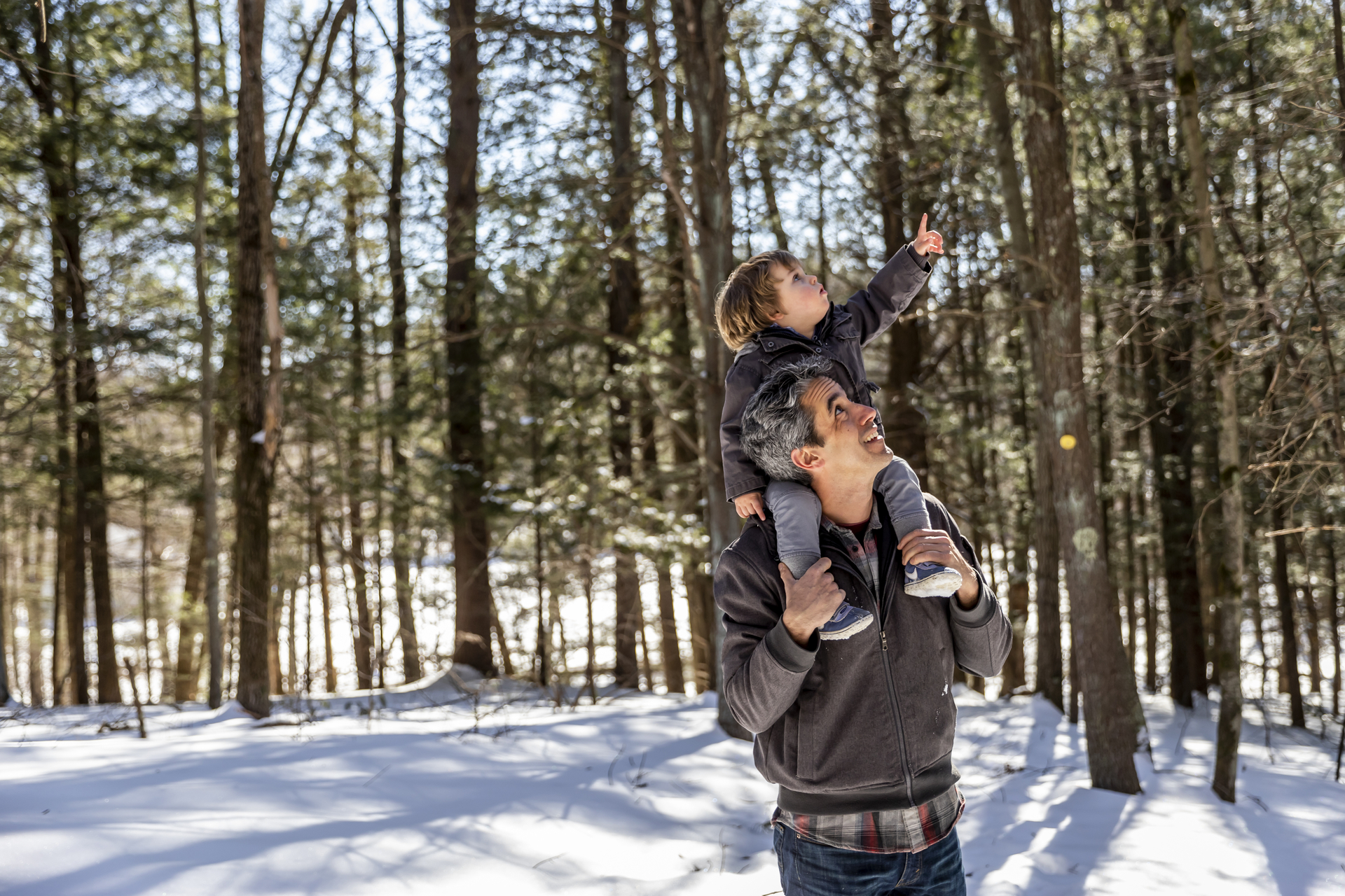 man with child on shoulders smiling and pointing into distance