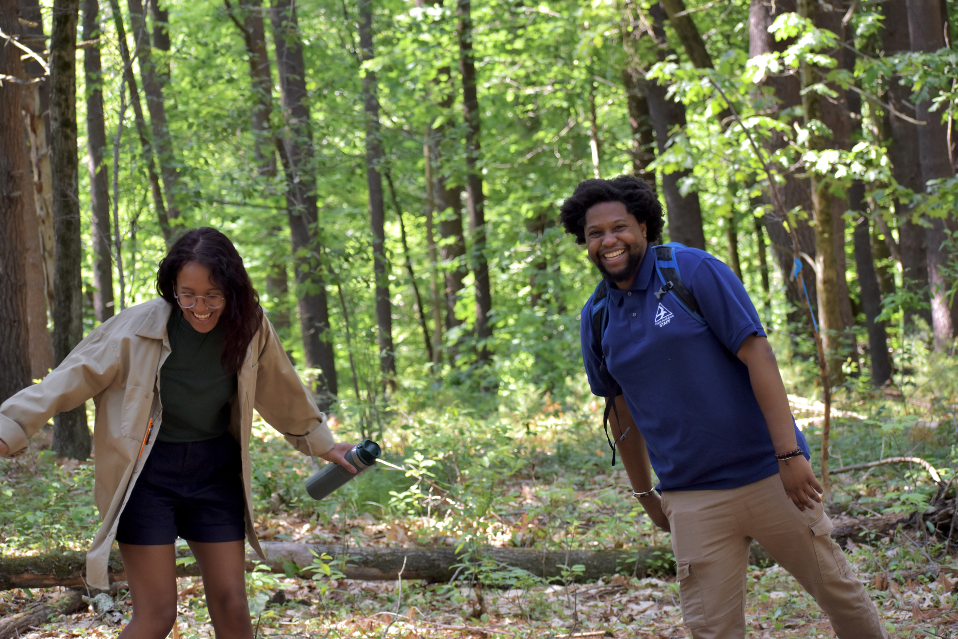 Environmental Fellowship Program fellows Bella and Jovan laugh in the forest.