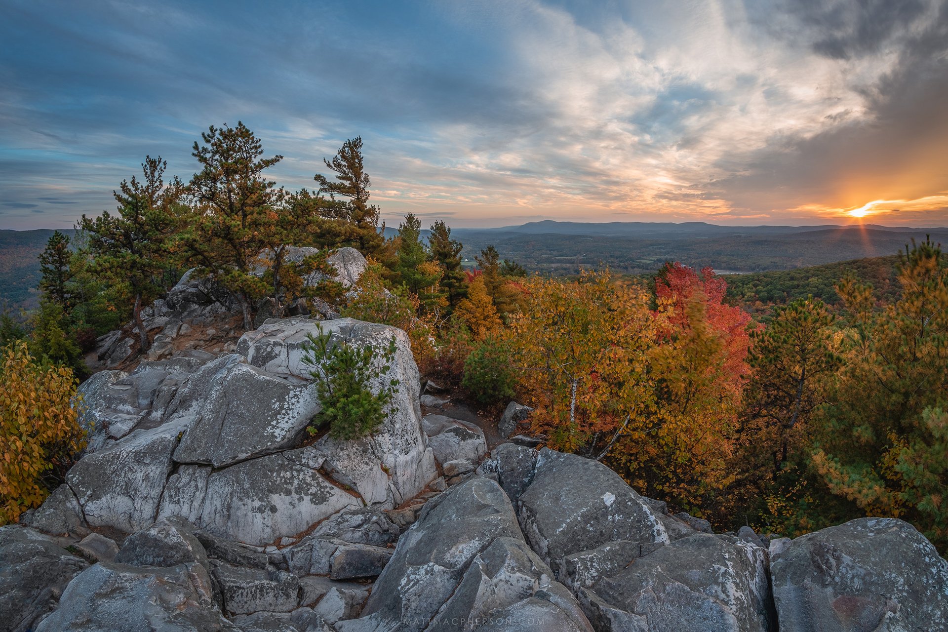 Rocks, fall foliage, and sunset in the distance