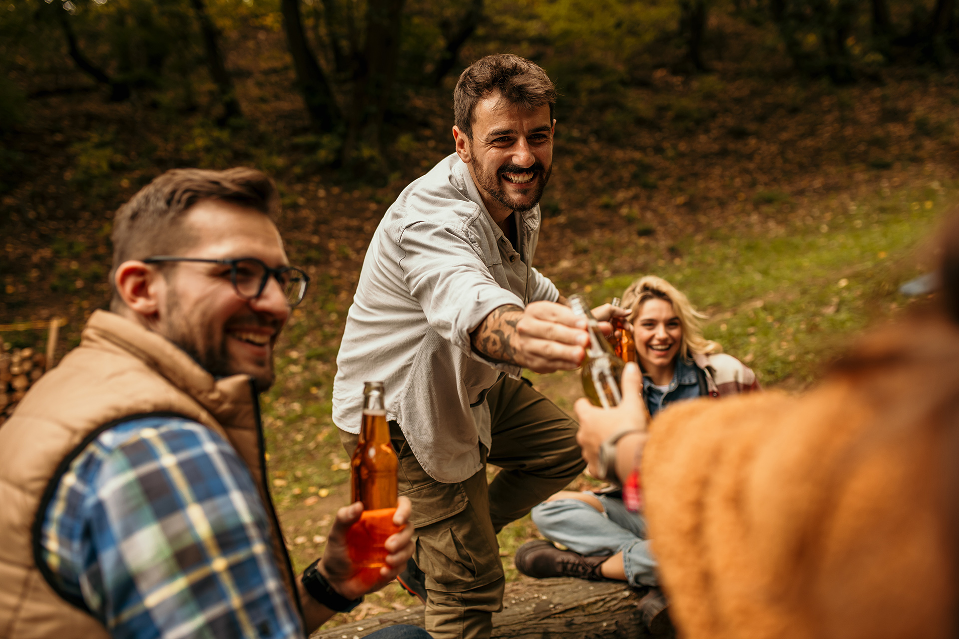 Group of young adults clinking bottles at a picnic table