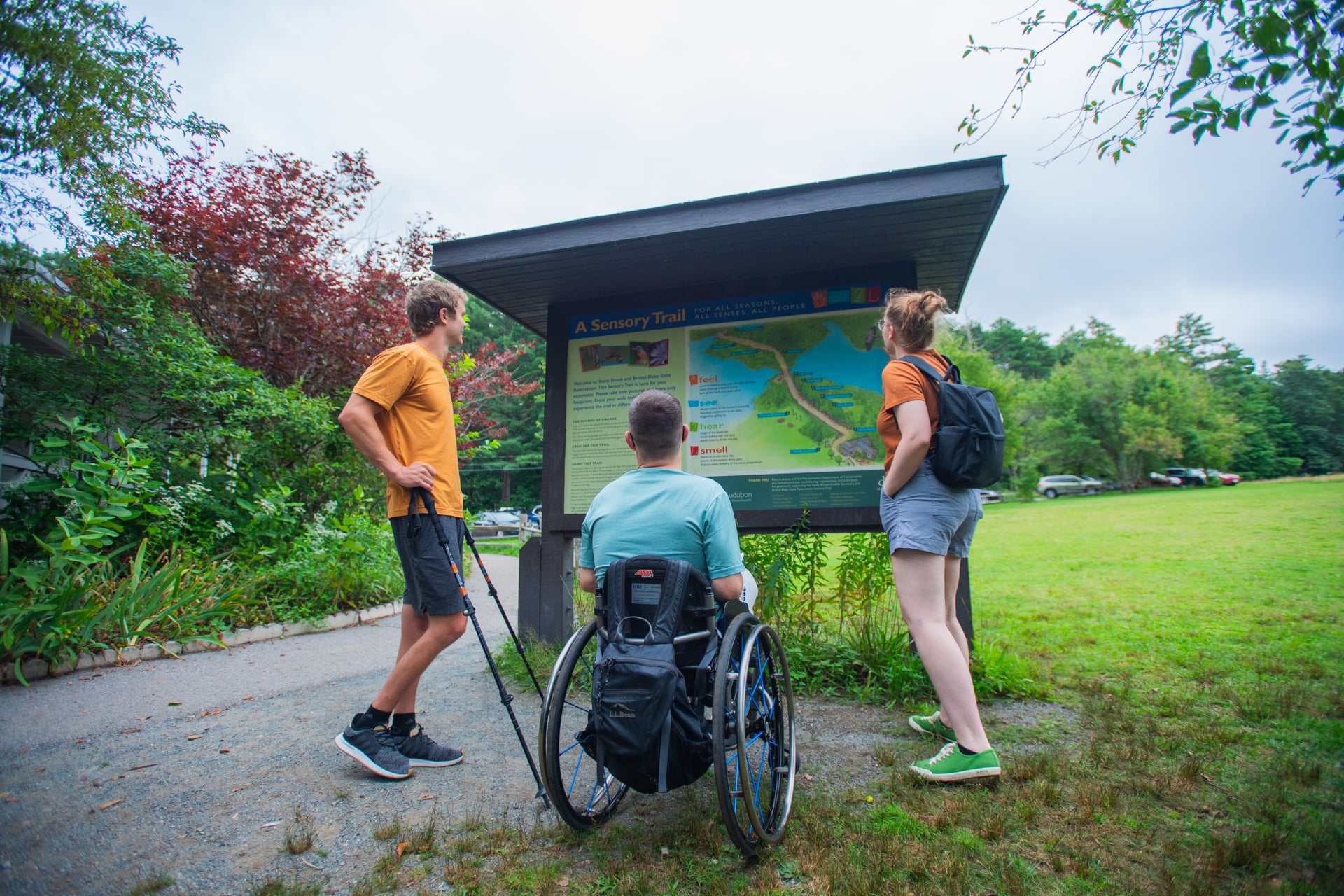 Group of three people looking at the map for an All Persons Trail