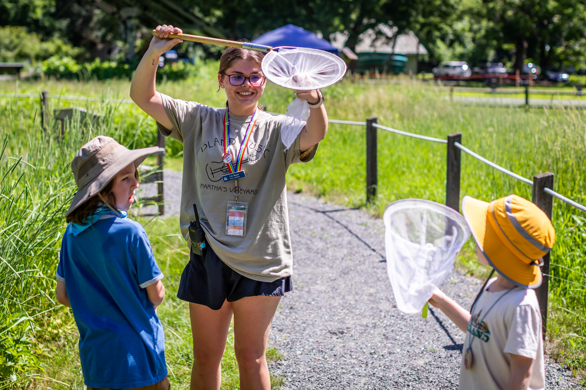 A counselor holds up a net to two small campers, smiling.