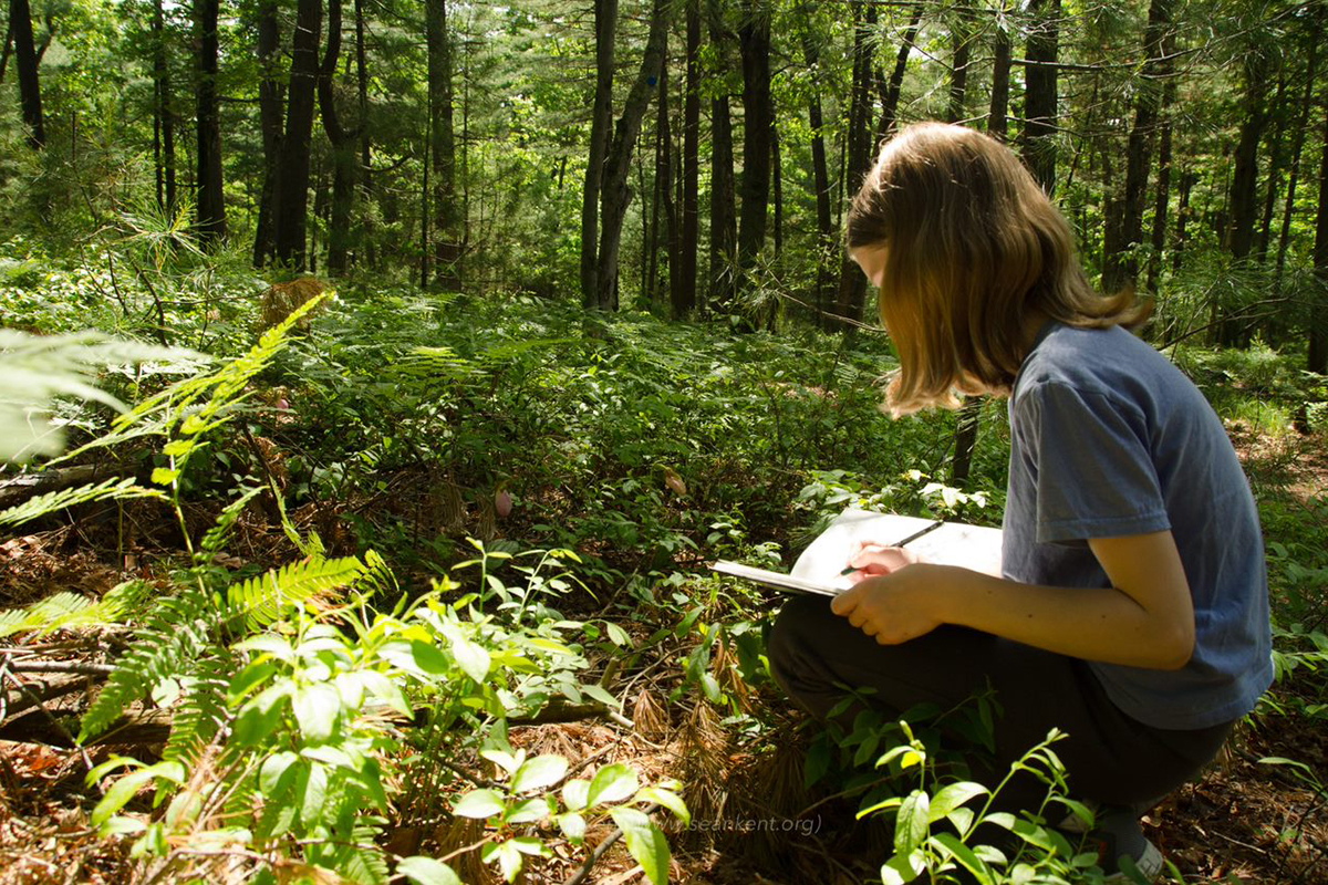 Girl sitting outside writing in a notebook
