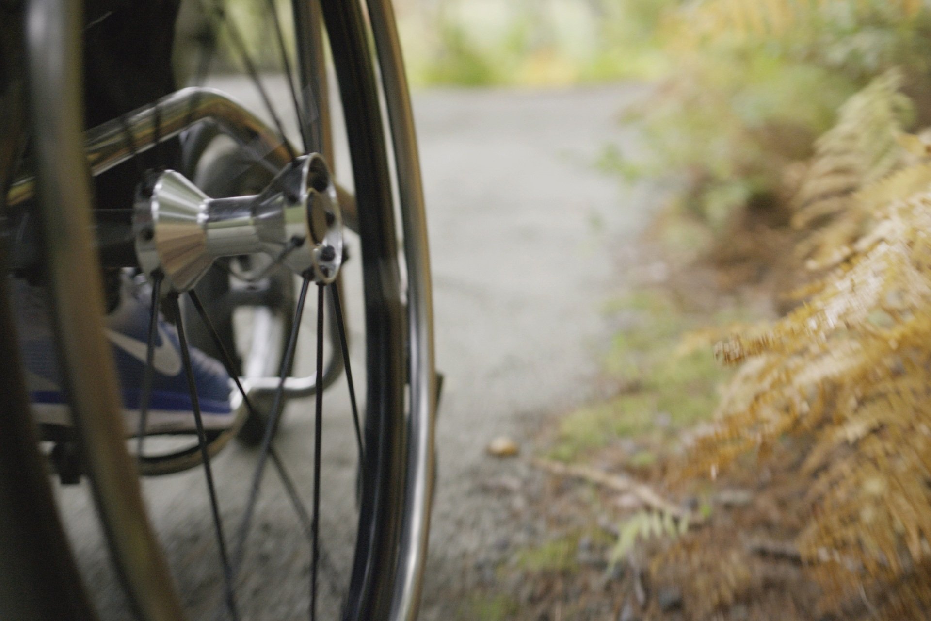 Closeup of the side of a wheelchair on an outdoor trail