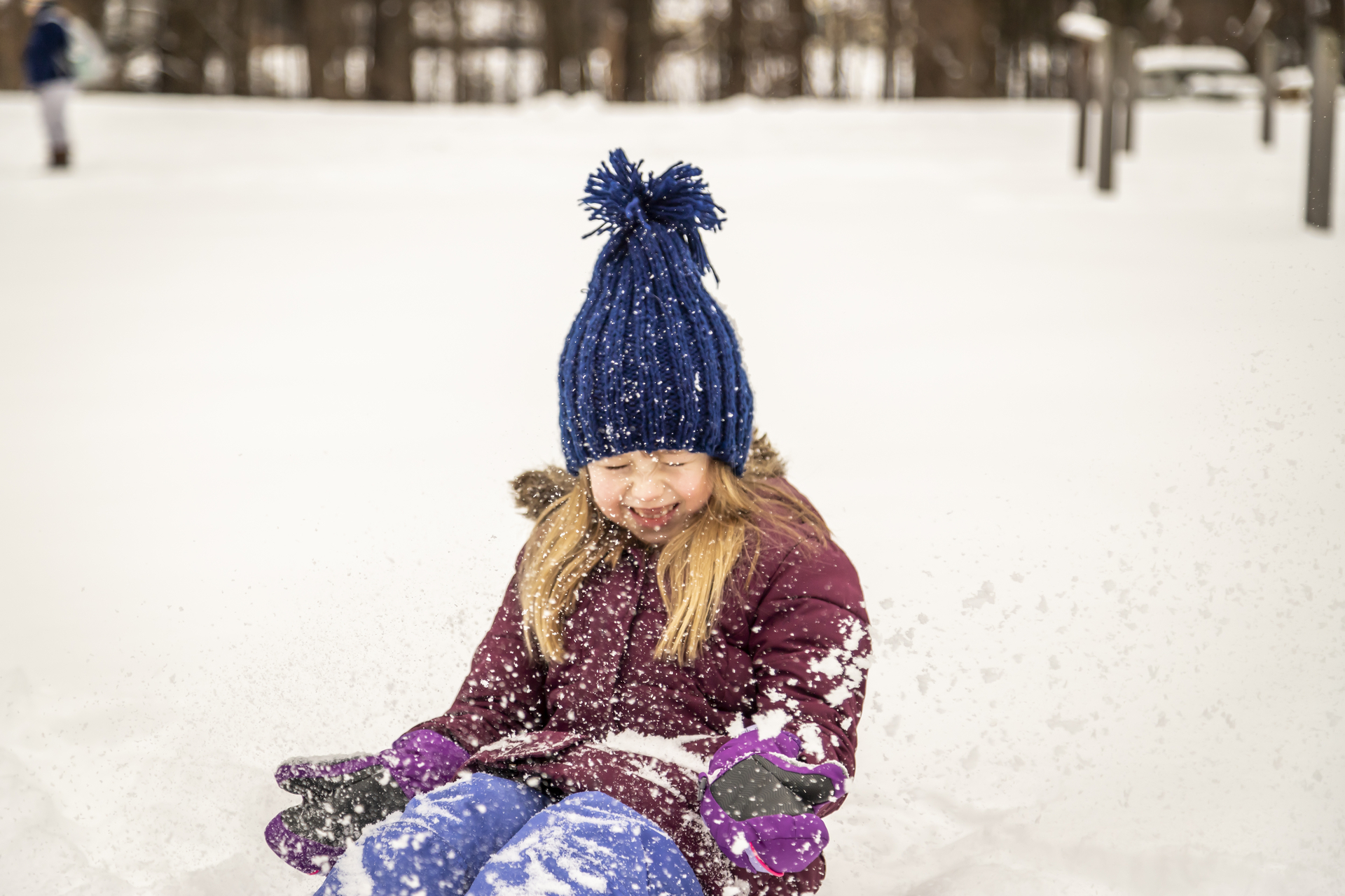 Girl in winter gear throwing snow and smiling