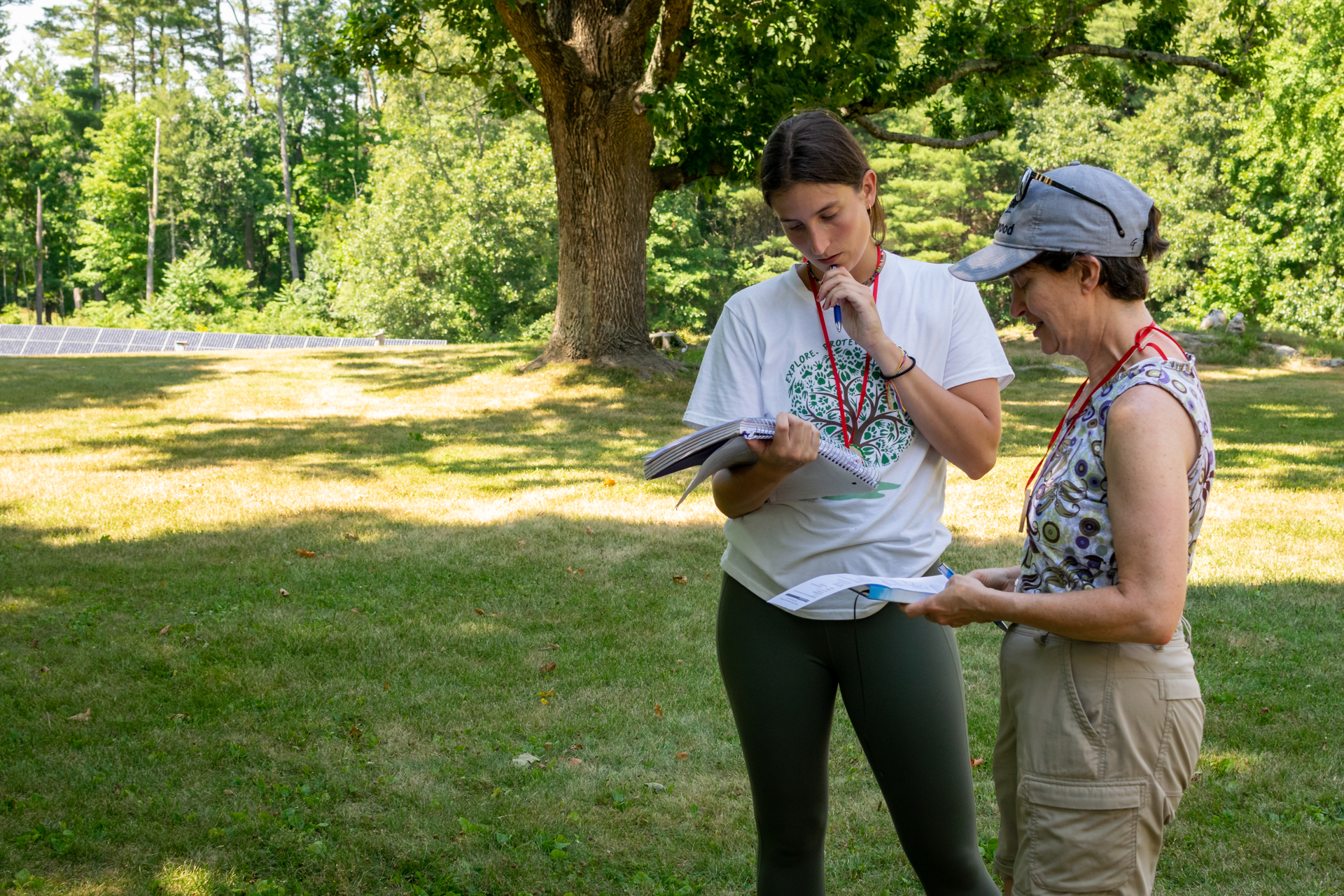 two teachers standing outside looking at notebooks