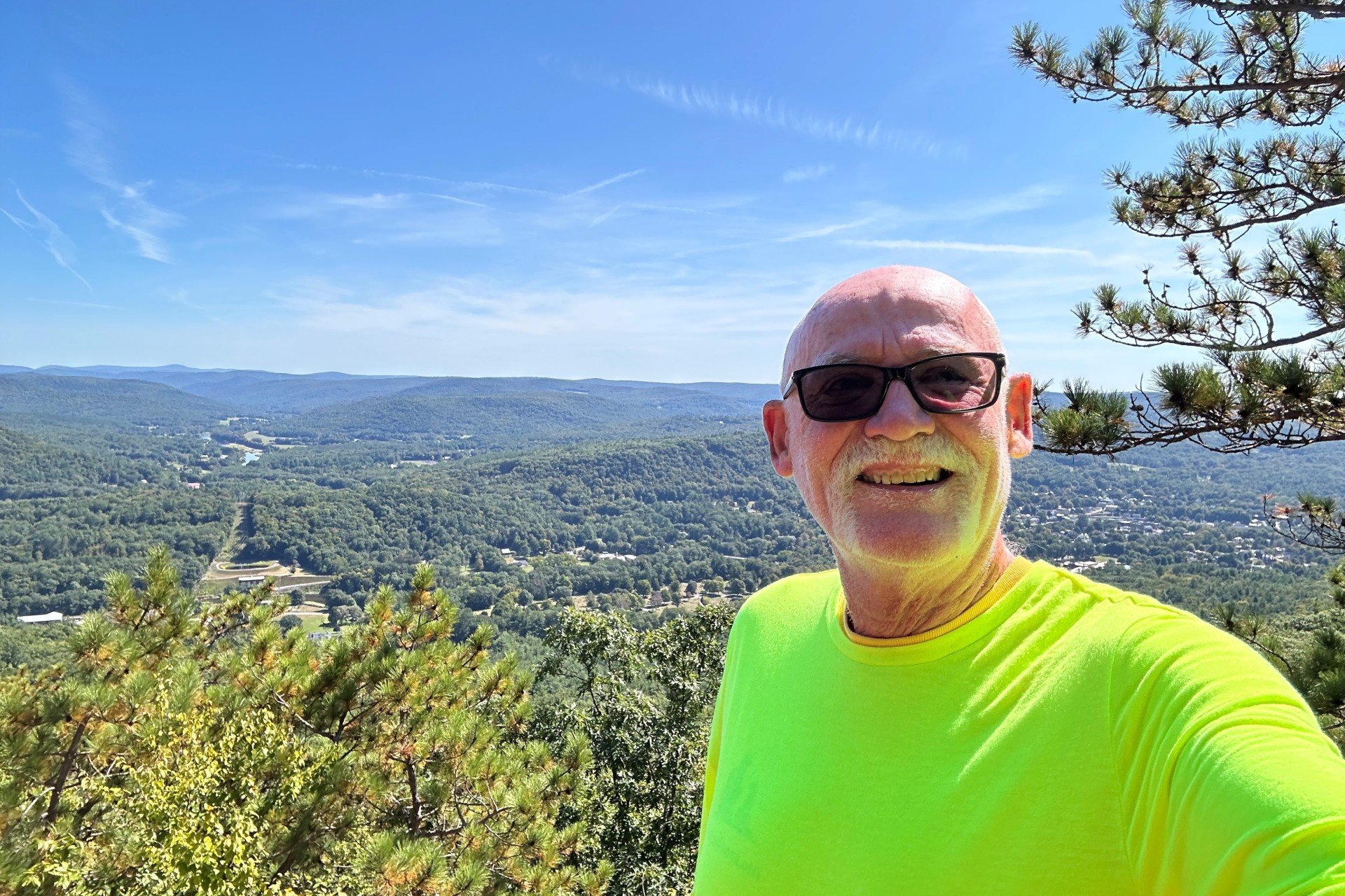 Andy Tolland smiling at camera with scenic view in back