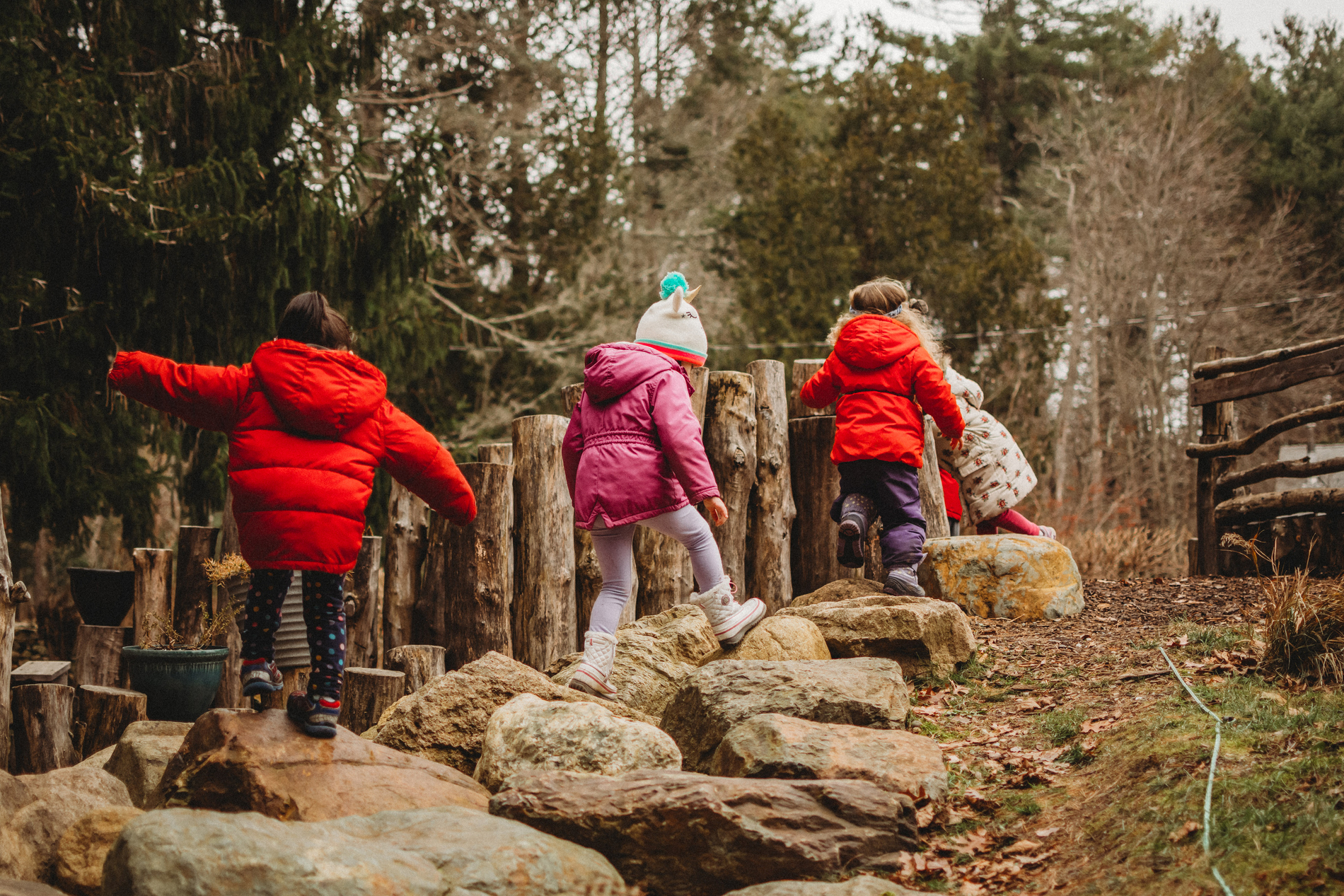 Kids in winter coats climbing rocks in a nature play area